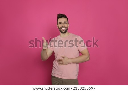 Happy man touching his belly and showing thumb up on pink background. Concept of healthy stomach Royalty-Free Stock Photo #2138255597