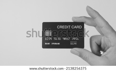 Hand is holding black credit card isolated on white background.Black and white picture.