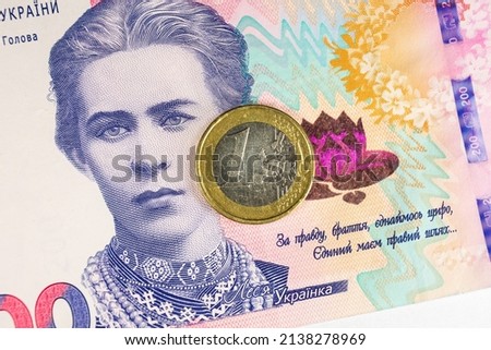 Poland — March 08 2022: In this photo illustration obverse of the 1 Euro coin and Ukrainian 200 hryvnias banknote with the image of Lesya Ukrainka are seen displayed.