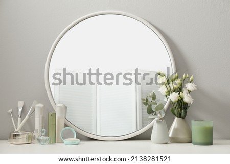 Stylish round mirror on dressing table with cosmetic products and flowers Royalty-Free Stock Photo #2138281521