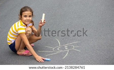 the child draws with chalk on the pavement, the heart is the sun. Nature. selective focus