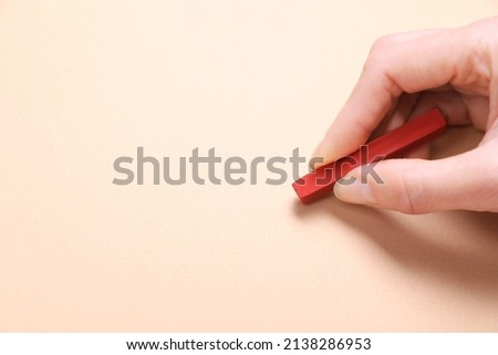 Woman drawing on beige paper with pastel, closeup. Space for text