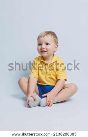 Little boy 3 years old in a yellow T-shirt and blue shorts, a boy in a sports uniform.