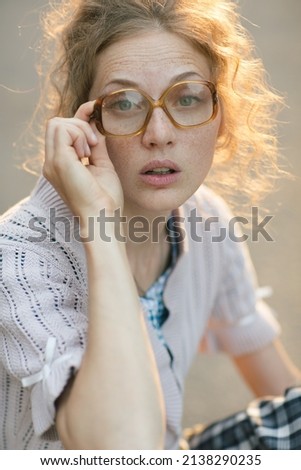 cheerful girl with poor eyesight on the street does not see well, expressing emotions. glasses concept  Royalty-Free Stock Photo #2138290235