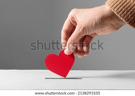 charity, love and valentine's day concept - close up of hand putting red heart into donation box Royalty-Free Stock Photo #2138293105