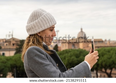 A young woman wearing white hat taking a picture with her mobile phone in Rome Italy