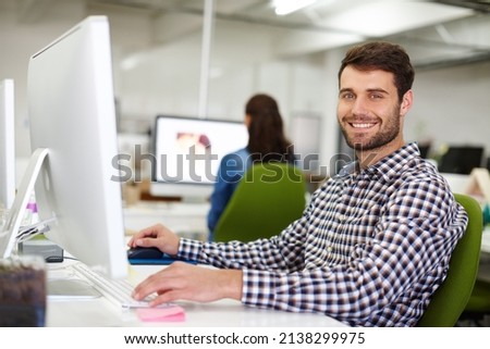 Im working on something big. Portrait of a handsome young designer sitting at his desk with a colleague in the background. Royalty-Free Stock Photo #2138299975
