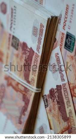 A bundle of paper 5000 Russian banknotes tied with a rubber band lies on a clockwise rotating platform covered with five thousand banknotes