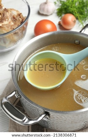Delicious homemade bone broth and ingredients on white wooden table