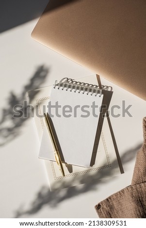 Spiral flip notebook with blank copy space, pen, laptop computer in flowers sunlight shadow on white table. Aesthetic bohemian minimalist workspace. Artist, writer template Royalty-Free Stock Photo #2138309531