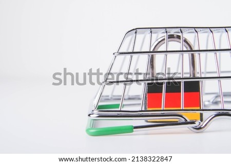 German sanctions. Closed castle with german flag. Cancellation of deliveries of products from Germany. Prohibition of supplies. Empty grocery basket and padlock.