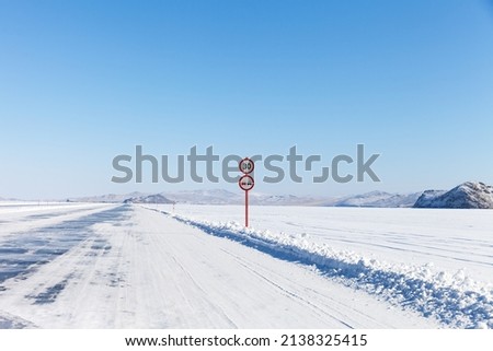 Baikal Lake in winter. Road signs on the ice road to Olkhon Island. Extreme driving on the ice crossing over the frozen Small Sea Strait at cold February day. Winter travel and adventure concept