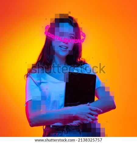 Contemporary artwork. Ypung girl with pixel head and neon lettering around holding tablet isolated over orange background in neon. Concept of digitalization, artificial intelligence, technology era