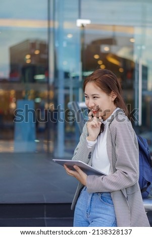 Asian woman publicly uses their laptop to study and work outdoors in shopping malls.	