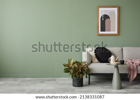 Creative living room interior composition with modern sofa, home decorations and personal accessories. Eucalyptus wall. Template. Copy space.