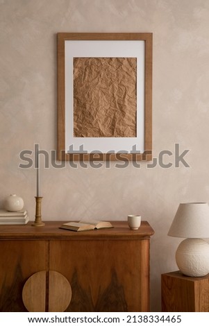 Interior design of neutral living room with stylish retro commode, mock up poster frame, table lamp and elegant personal accessories in home decor. Template. Japandi concept.
