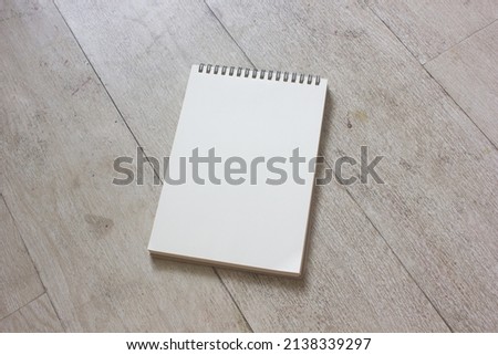The blank page of vertical spiral spine sketchbook for education, diary, message memory, business schedule mockup, on texture wooden background.