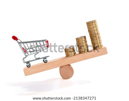 Inflation. Shopping and money. Coin and shopping trolley on wooden seesaw. Supermarket shopping trolley. Concept of growth of food sales, growth of market basket or consumer price index. Royalty-Free Stock Photo #2138347271