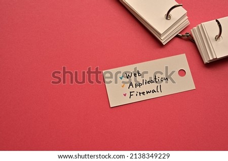 There is a small card placed on a red background paper with the word Web Application Firewall written on it. Copy space available.
