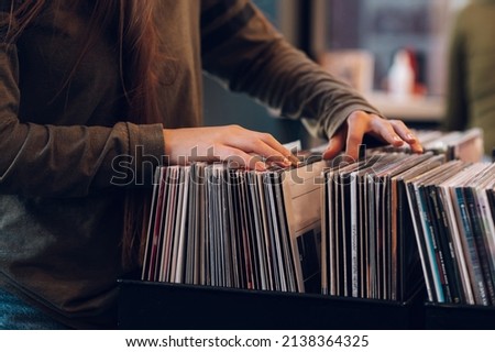 Close shot of a woman hands browsing records in the vinyl record store. Audiophile and music lover. Vintage Vinyl LP In Records Shop. Royalty-Free Stock Photo #2138364325
