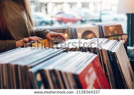 Close shot of a woman hands browsing records in the vinyl record store. Audiophile and music lover. Vintage Vinyl LP In Records Shop. Royalty-Free Stock Photo #2138364337
