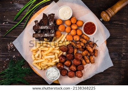 wooden tray with beer snacks, snacks for beer with different sauces on parchment Royalty-Free Stock Photo #2138368225