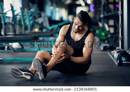 Sport Injury. Upset Arab Male Athlete Suffering From Knee Trauma While Training At Gym, Middle Eastern Man Sitting On Floor And Massaging Aching Area, Sporty Guy Frowning With Pain, Copy Space Royalty-Free Stock Photo #2138368801