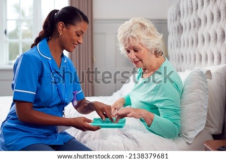 Female Care Worker In Uniform Helping Senior Woman At Home In Bed With Medication Royalty-Free Stock Photo #2138379681