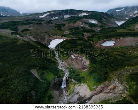 Shooting from a drone. Waterfall in Kamchatka, on the background of a green landscape