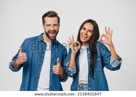 Young caucasian couple man and woman husband and wife spouses boyfriend and girlfriend showing thumbs up and okay gesture looking at camera isolated in white background. Quality check