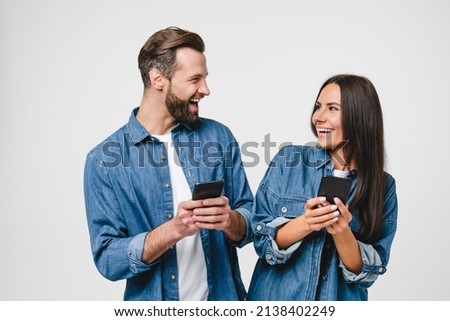 Young mobile users, loving couple spouses girlfriend and boyfriend using smart phones together looking at each other, surfing on internet online, e-commerce, e-banking isolated in white background Royalty-Free Stock Photo #2138402249