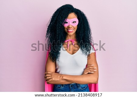 Middle age african american woman wearing super hero costume happy face smiling with crossed arms looking at the camera. positive person. 