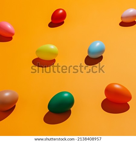 Multicolor eggs with trendy summer shadows on vibrant orange background. Creative food concept. Geometrical Easter pattern or texture. Flat lay.