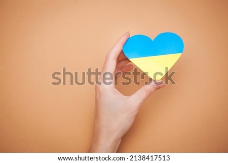 Heart with print the national flag of ukraine in female hands.