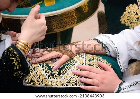 Artist applying henna tattoo on women hands. Mehndi is traditional moroccan decorative art. Close-up, top view
