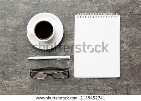 Modern office desk table with notebook and other supplies with cup of coffee. Blank notebook page for you design. Top view, flat lay.