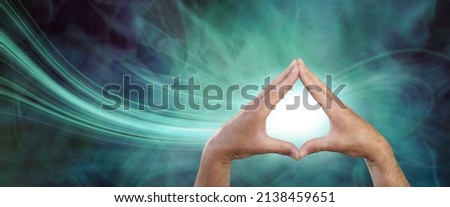 Healer attracting scalar energy with palm chakras - male hands touching fingertips together with a white orb between against a green navy blue energy field and a stream of energy flowing in
 Royalty-Free Stock Photo #2138459651