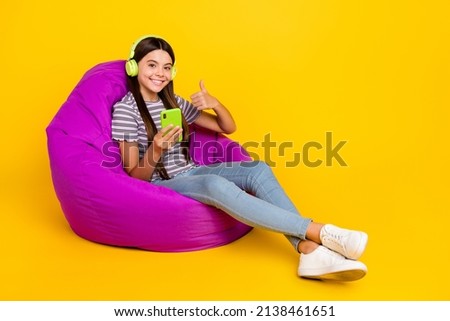 Full body profile side photo of young girl chair use mobile meloman show thumb-up good perfect isolated over yellow color background