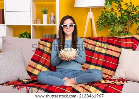Full size portrait of cheerful lady sit couch hold popcorn plate isolated on yellow color background