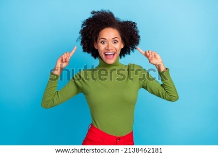 Photo of excited funky girl indicate fingers wavy hair have good mood isolated on blue color background