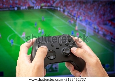 Man holding game controller playing football game. Royalty-Free Stock Photo #2138462737