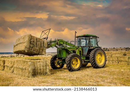 A ranch worker moving bales of hay with a farm tractor on a ranch near Paulina, Oregon Royalty-Free Stock Photo #2138466013