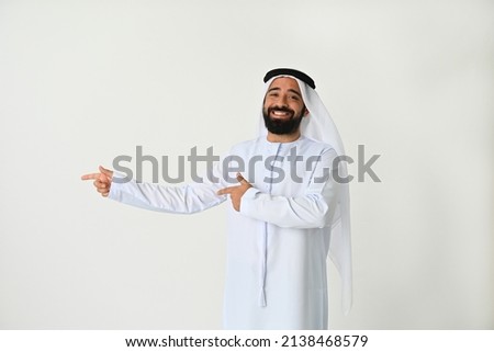 Happy Emirati man pointing to side presenting an offer and excited to show Royalty-Free Stock Photo #2138468579