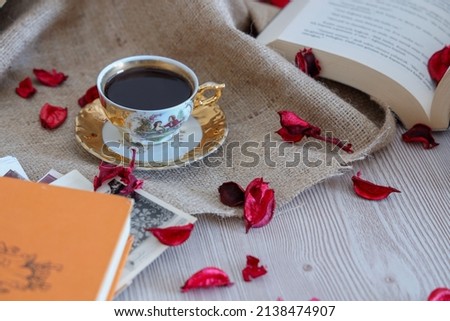 Turkısh Coffee in classic cup, wooden background with romantic rose petals, book about love among old vintage pictures, decorate with beige color fabric. Copy space.