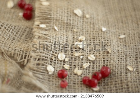 oatmeal and red currant berries scattered on burlap with space for text