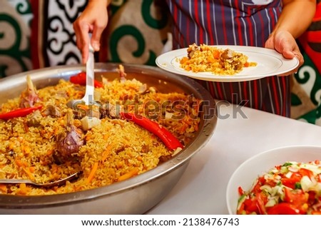 Catering  food prepares a festive dish Pilaf Traditional Central Asian festive cuisine in national style. Cooking. Nauryz. Selective focus. Shallow depth of field. Royalty-Free Stock Photo #2138476743
