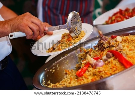 Pilaf is placed in a white plate. Traditional Central Asian festive cuisine. Catering food in traditional national style. Cooking. Nauryz. Selective focus. Shallow depth of field. Royalty-Free Stock Photo #2138476745