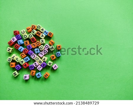 Alphabet distribution of colorful letters on a green background.