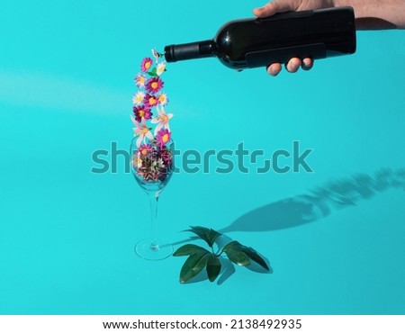 Spring is poured. Horizontal flat lay compsition on a pastel cyan basground with male hand, wine bottle. glass and flowers. Minimal spring celebration concept Royalty-Free Stock Photo #2138492935