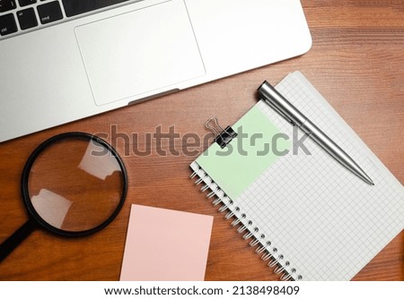 Business notebook with laptop and magnifier at desk. High quality photo
